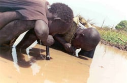 Sudanese boys using pipe filters to avoid contracting dracunculiasis.