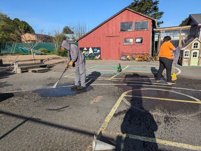 Pressure washing and sweeping off the blacktop the designs are to be painted