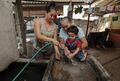 Yessica González lava las manos de su pequeño hijo, Josué, en casa de su madre en el municipio de El Paisnal en El Salvador. Azure trabajó con la municipalidad para reparar el sistema de agua y restaurar el servicio en su hogar. Foto por Oscar Leiva/Silverlight para CRS.