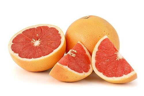 A pink grapefruit shown whole, halved, and in segments