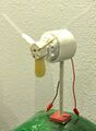 This image shows a wind mill made , wooded dowel, and wooden propellers with plastic extensions.