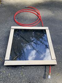 Image of first prototype of solar collector. Features 100 feet of 1/2" diameter PEX tubing painted black and covered with an acrylic panel in a 33" x 33" box.
