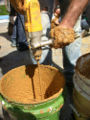 Mixing clay found on-site for the clay-slip-straw using a power drill with a paint mixing paddle