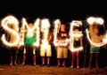 A group of people writing out "smile" with sparklers.