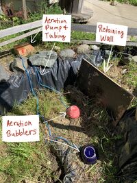 Image 5: Shows aeration system pump and bubblers with tubing and retaining wall.