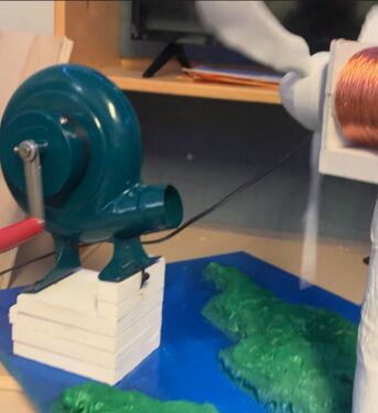 Utilice bloques de madera para crear una plataforma que incline el ventilador de manivela hacia las aspas de la turbina; Cierre con brida o pegue el ventilador a la plataforma y pinte de blanco.