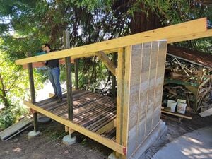 Lonny chainsawing off tops of 4"x4" posts to level them to roof
