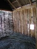 Fig 2: This photo shows the weaving of the wattle panels. The maleable twigs/branches shown on the floor are used weaving. These twigs/branches are often called withies.
