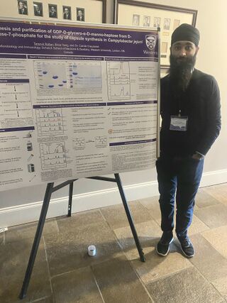 Picture of Taranvir beside a poster he presented at a research conference.