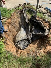 Image 2: After digging out the soil and other debris from the bottom of the pond, the liner was gathered up to in preparation to be removed.