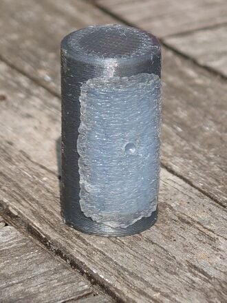 The image shows a 3D-printed cylinder with a grippy, textured hot-glue insert on one side.