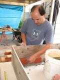 To minimize conductive heat loss to the metal table, and to assure good adhesion of bricks, a sheet of ½" Hardibacker was laid on the table as a base for the stove to be built. The sheet was scored, cut and centered on the tabletop. The wood mold was centered on the fireboard, prior to beginning stove construction. Bricklaying was started inside the front left-corner of the wood mold.