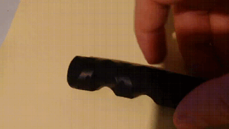 The GIF depicts a prosthetic finger consisting of three phalanxes wrapped in a black, textured heat shrink tubing. The finger is actuated (bent) and springs back into the original form, after being released.