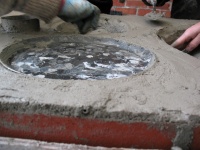 Outside of the burner boundary, clay was added to the top of the final brick course. Inside the burner boundary, a 2 to 3 cm layer of clay was added from the top of combustion chamber brick course. The objective in building up the clay above the combustion chamber was to create a 2 cm vertical gap below the bottom of the burner
