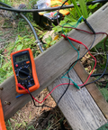 Connecting the multimeter to the pump to test current by inserting it into a break in the wires leading from the pump to the panel