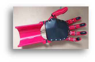 This photo depicts the final version 4 of the hand prosthesis laying flat on a table. The prosthesis is printed from red PETG with black latex inserts on the fingertips and on the palm. You can see white Dyneema strings as tensors.