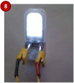 Un-hook wires from volt meter, and hook the wires to the light. Set up with the light oriented as shown in the picture. Clip the red wire on the positive terminal (right side) of the light and the black wire to the negative terminal (left side). Crank the drill to power the electronics.