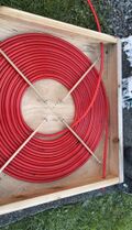 Obtain 100 feet of 1/2" diameter PEX tubing. Coil the tubing within the 36" x 36" box. Secure the coil with wooden dowels in an X Position. Drill the two 3/4" holes on opposite sides of the box to allow for the tubing to enter and exit the box.
