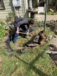 Image 1: Pond Deconstruction began with digging out the grass, clay, and rocks from the bottom of the pond.