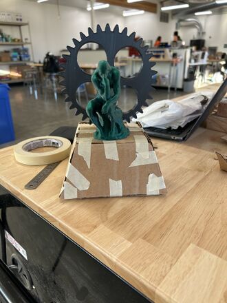 Thinker Gear- Truncated square base constructed out of cardboard with thinker figure and gear attached to base