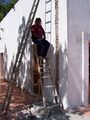 Cutting hole in Adobe wall to run PVC pipe to rooftop collector.