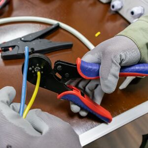 Two hands using the cable stripper to prepare the cable ends for crimping with the cable lugs.